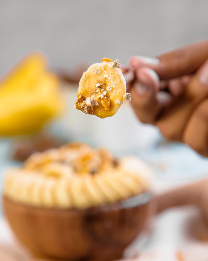 Close-up of a delicious banana dessert with a crumb topping held on a fork, set against a background.